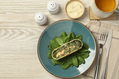Photo of Piece of delicious strudel with salmon and spinach served on light wooden table, flat lay. Space for text
