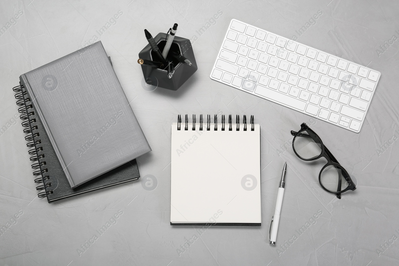 Photo of Flat lay composition with notebooks, keyboard and glasses on light grey table