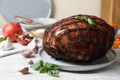 Photo of Delicious baked ham, basil leaves and garlic on white wooden table