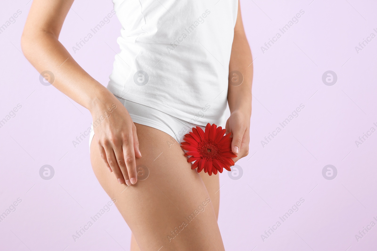 Photo of Young woman holding flower near underwear on color background. Gynecology