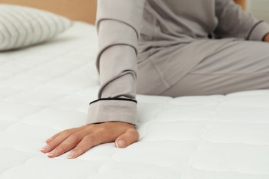 Photo of African American woman sitting on soft mattress in bedroom, closeup