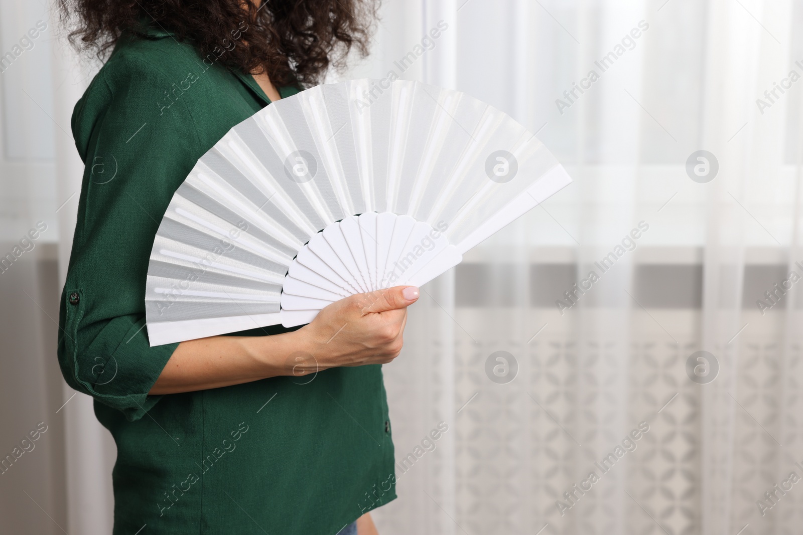 Photo of Woman with hand fan indoors, closeup. Space for text