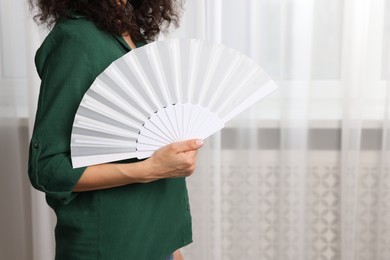 Photo of Woman with hand fan indoors, closeup. Space for text