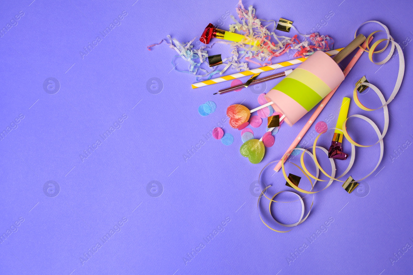 Photo of Party popper, lollipops and festive decor on violet background, flat lay