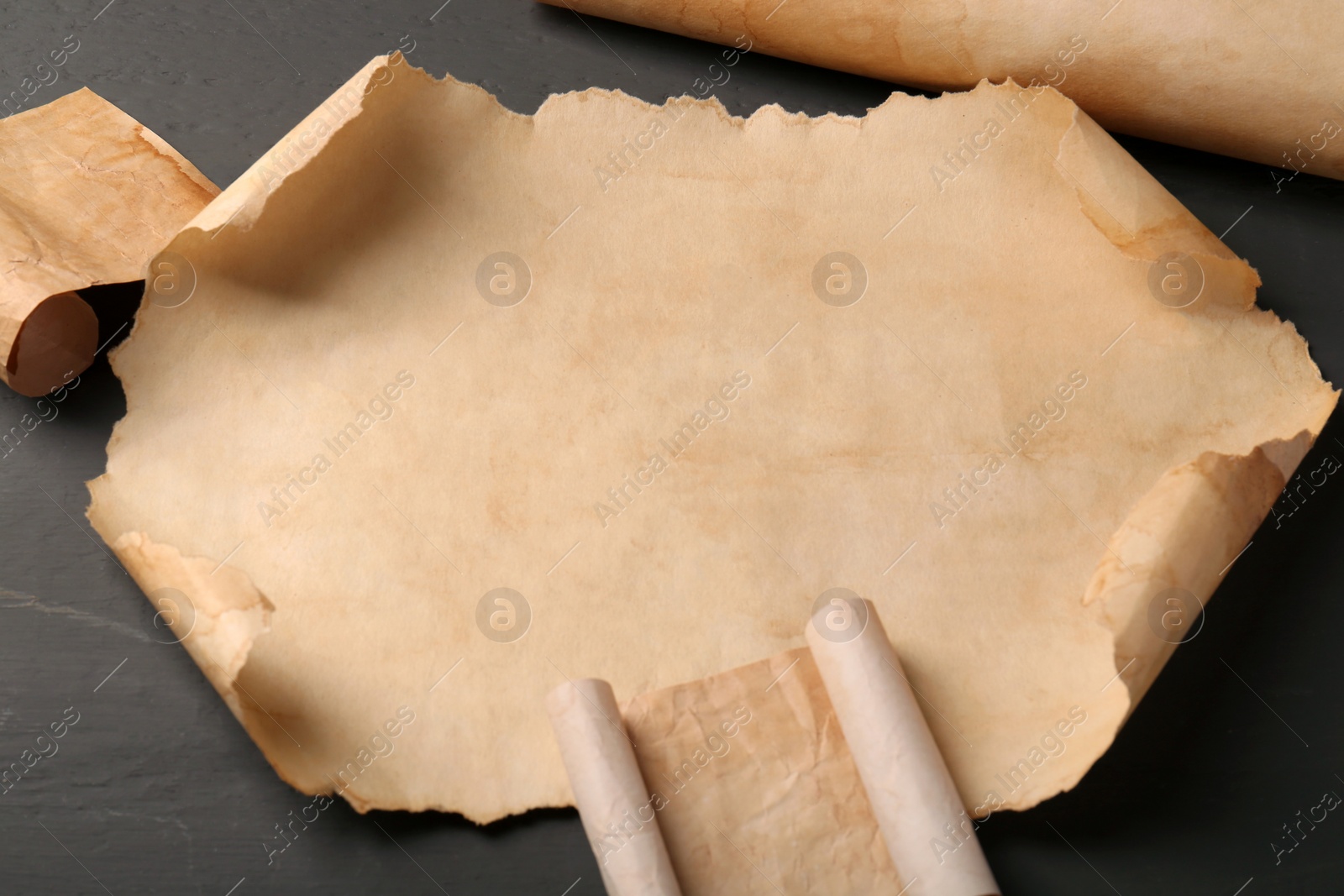 Photo of Sheets of old parchment paper on grey wooden table