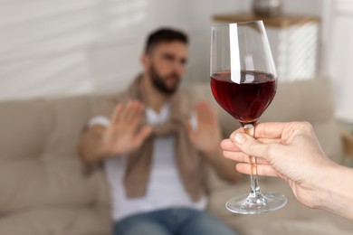 Photo of Man refusing to drink red wine indoors, closeup. Alcohol addiction