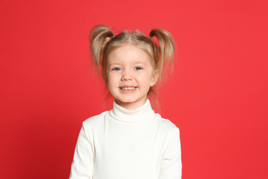 Portrait of cute little girl on red background