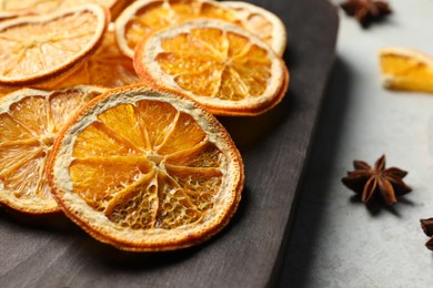 Photo of Dry orange slices and anise stars on light grey table, closeup