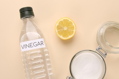 Eco friendly natural cleaners. Vinegar in bottle, cut lemon and jar of soda on beige background, flat lay