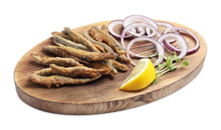 Wooden board with delicious fried anchovies, lemon, and onion rings on white background