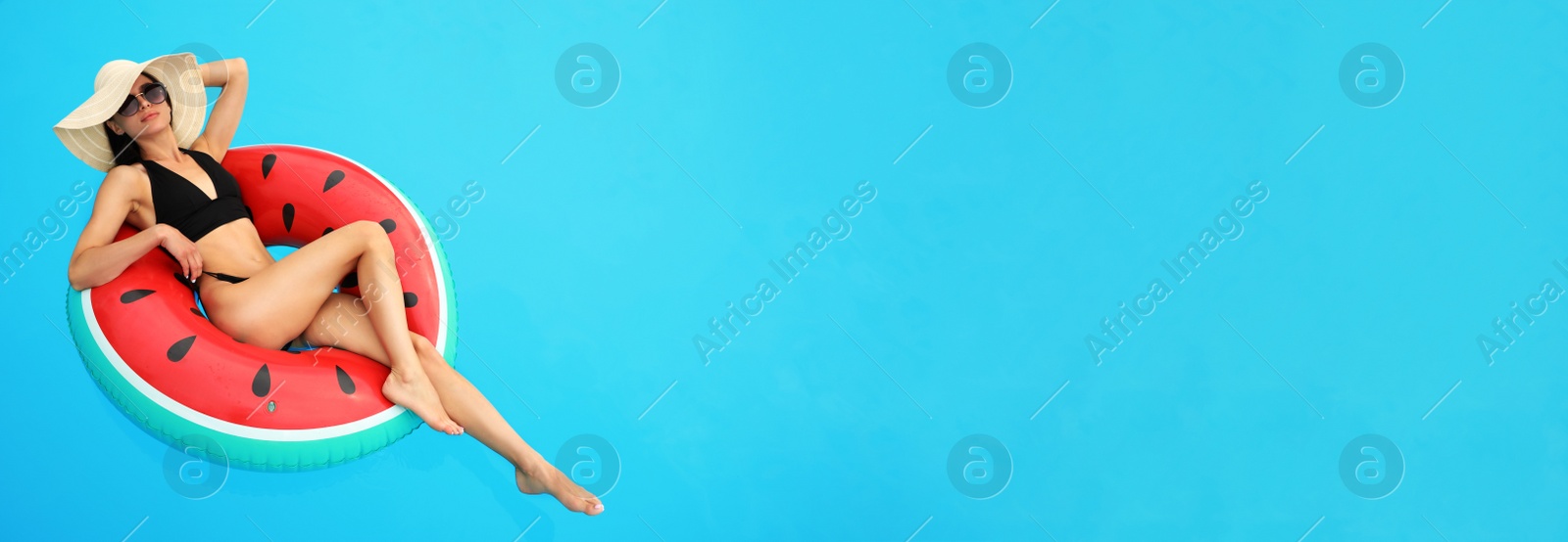 Image of Young woman wearing stylish black bikini on inflatable ring in swimming pool, space for text. Banner design