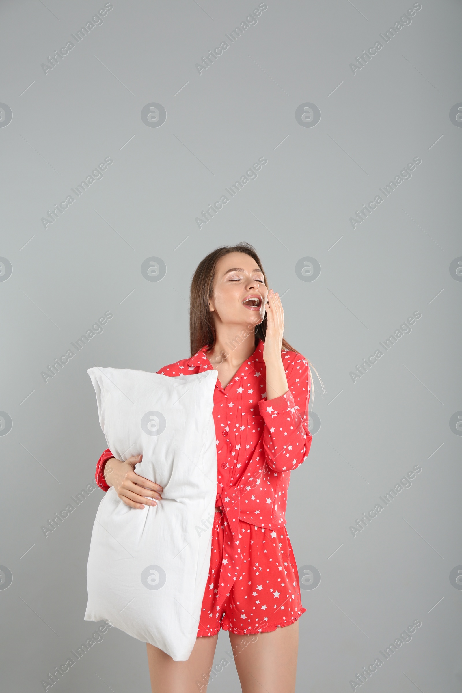 Photo of Young woman with pillow on grey background