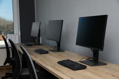 Photo of Open office interior. Modern workplaces with computers near light grey wall