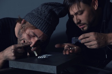 Photo of Young addicted men taking drugs on grey background