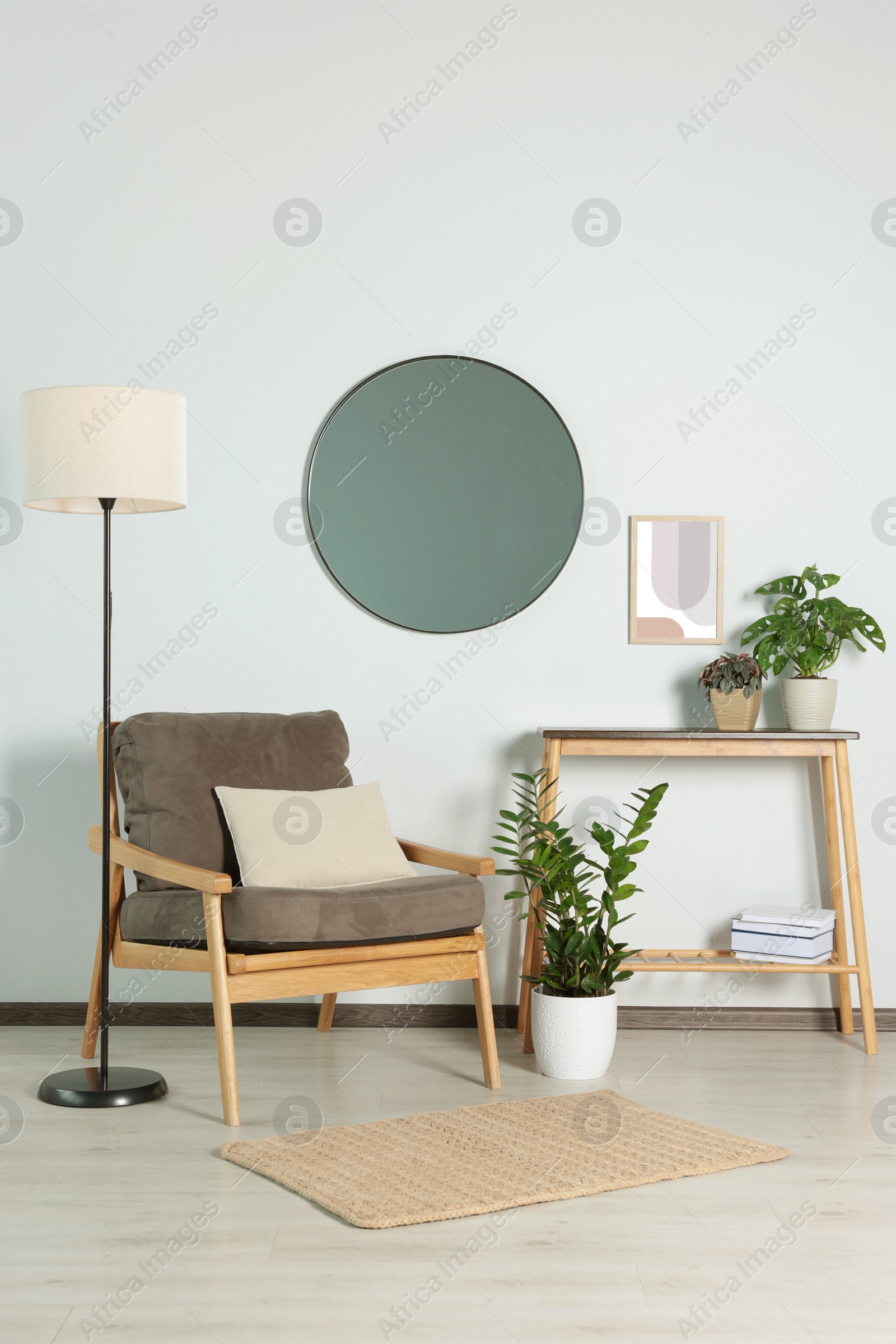 Photo of Stylish living room interior with wooden furniture, houseplants and round mirror on white wall