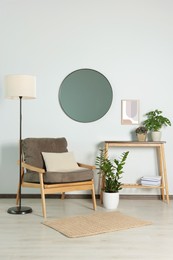 Stylish living room interior with wooden furniture, houseplants and round mirror on white wall