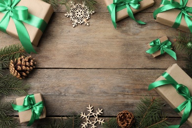 Photo of Frame of gift boxes and Christmas decorations on wooden table, flat lay. Space for text