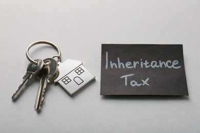 Photo of Card with phrase Inheritance Tax and keys with house shaped key chain on grey background
