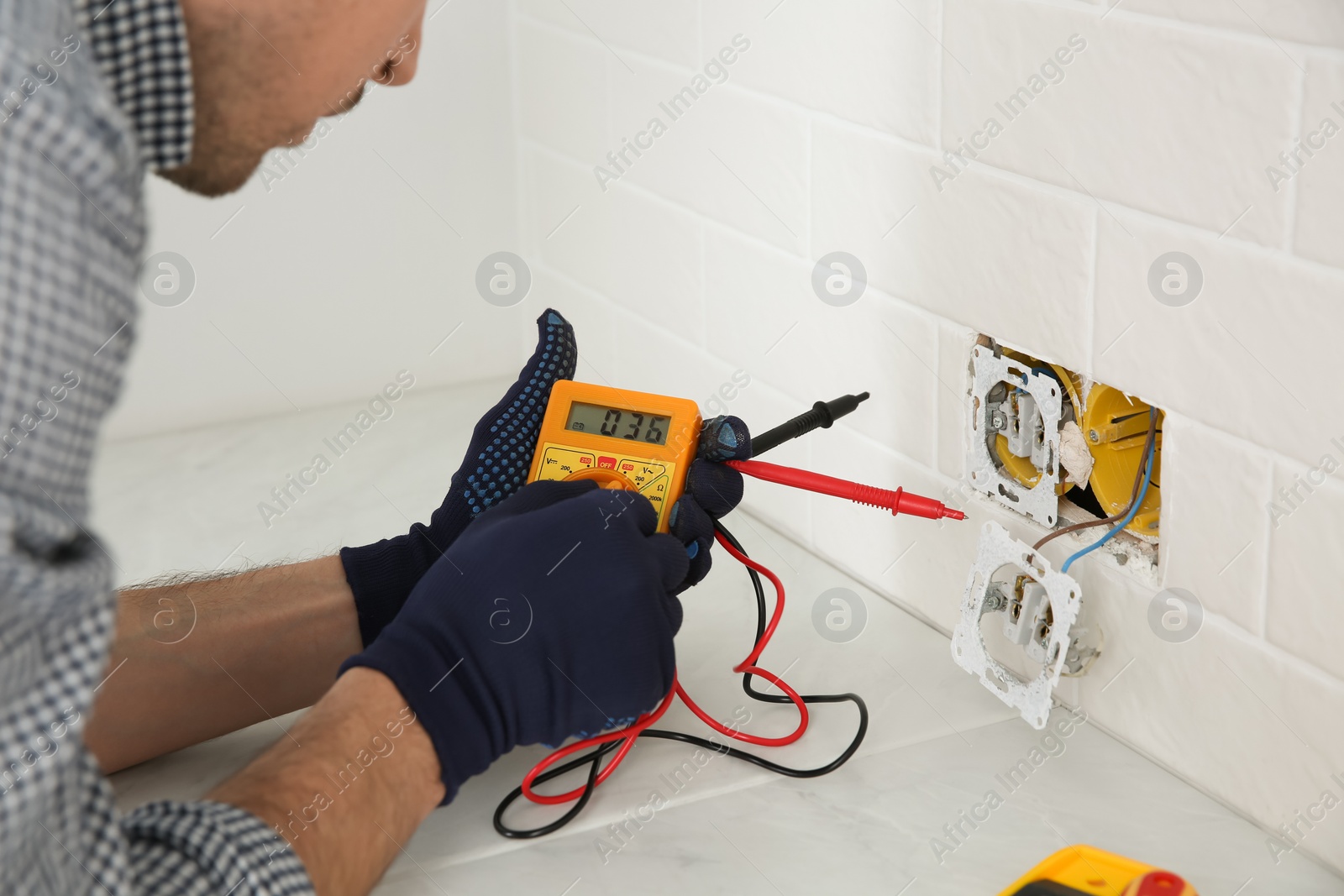 Photo of Electrician with tester checking voltage indoors, closeup