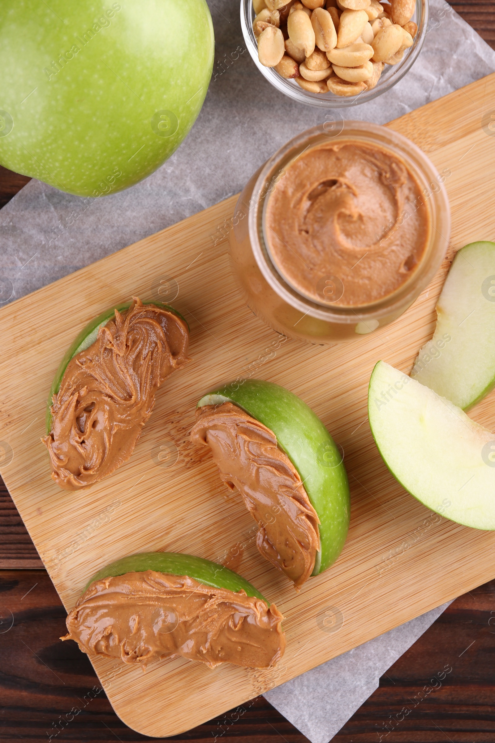 Photo of Slices of fresh green apple with peanut butter on wooden table, flat lay