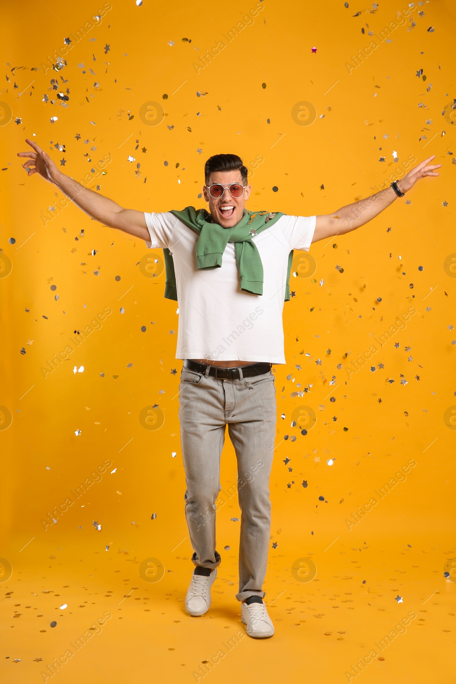 Photo of Happy man and confetti on yellow background