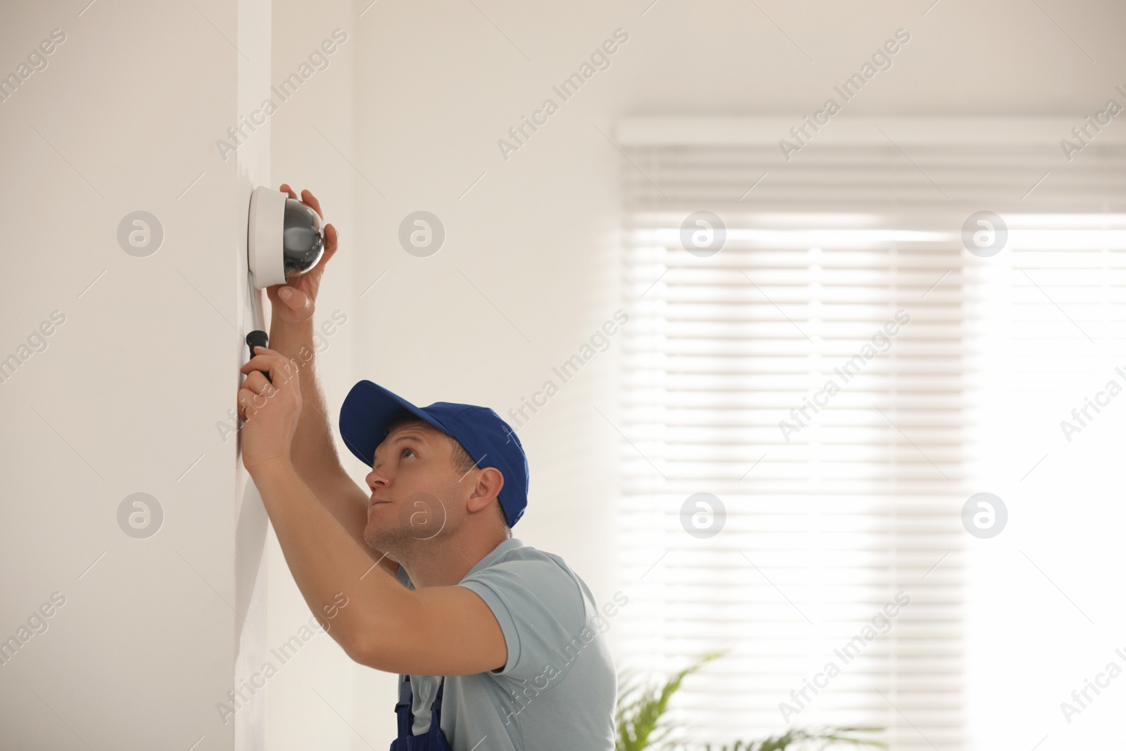 Photo of Technician installing CCTV camera on wall indoors