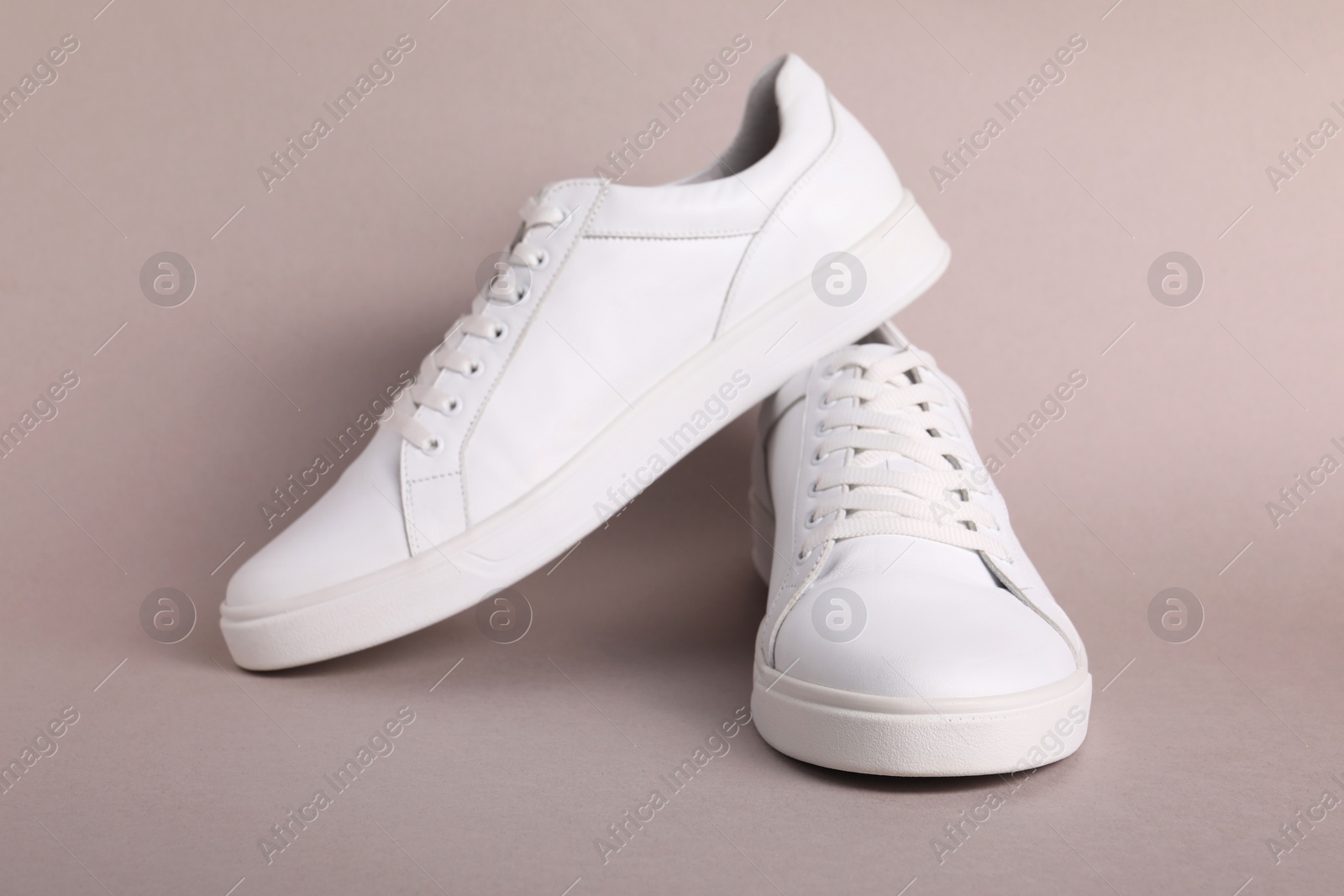 Photo of Pair of stylish white sneakers on grey background