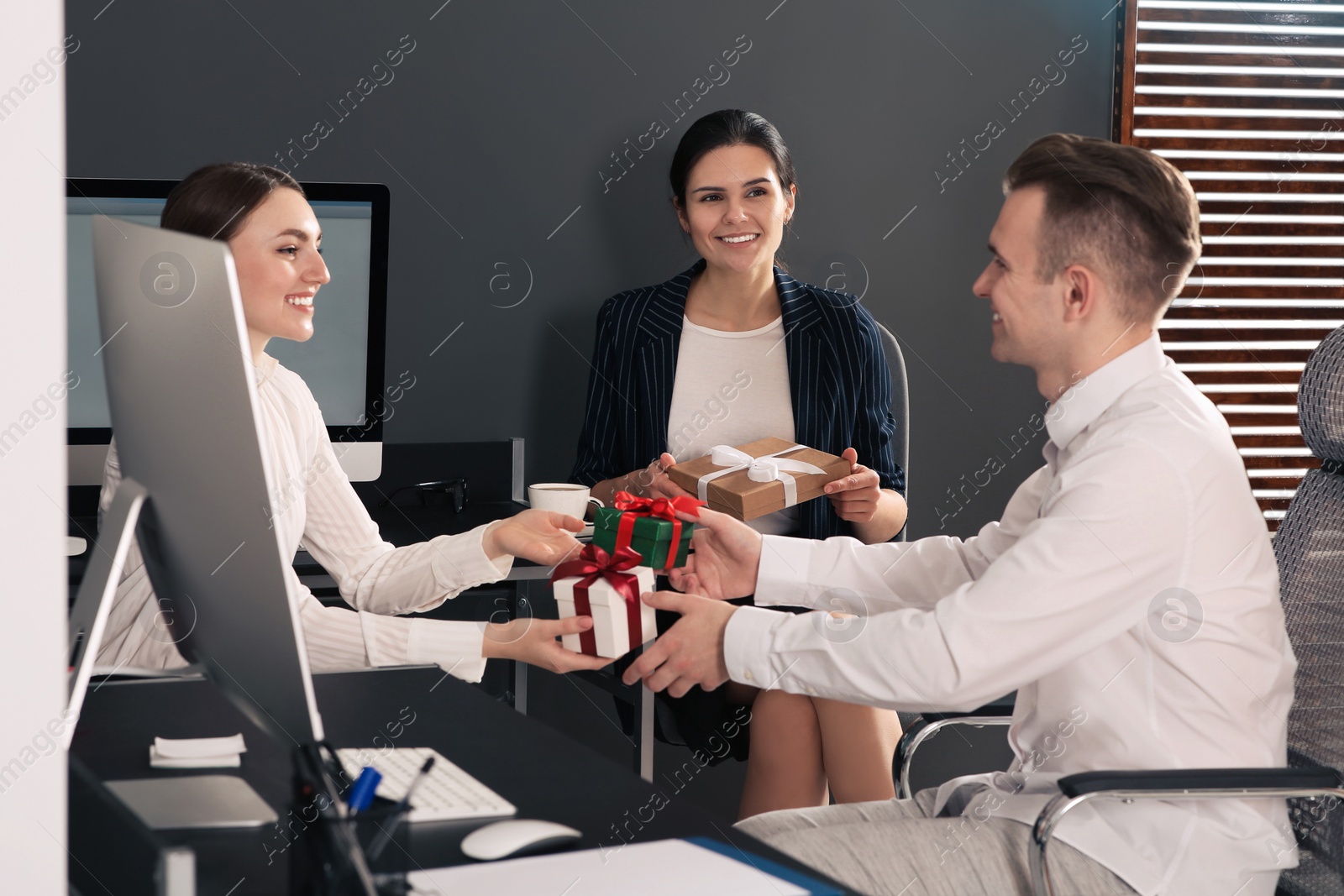 Photo of Colleagues presenting gifts each other in office