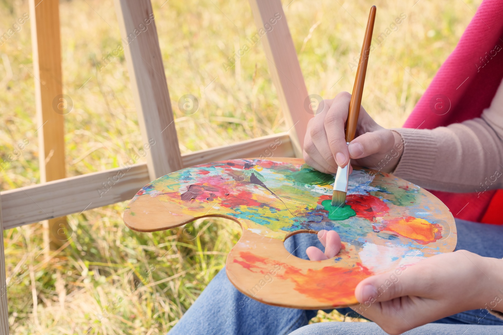 Photo of Young woman drawing with brush outdoors, closeup