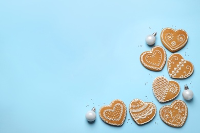 Tasty heart shaped gingerbread cookies and Christmas decor on light blue background, flat lay. Space for text