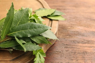 Photo of Aromatic bay leaves and different herbs on wooden table, space for text