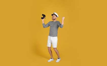 Photo of Happy sailor with binoculars on yellow background