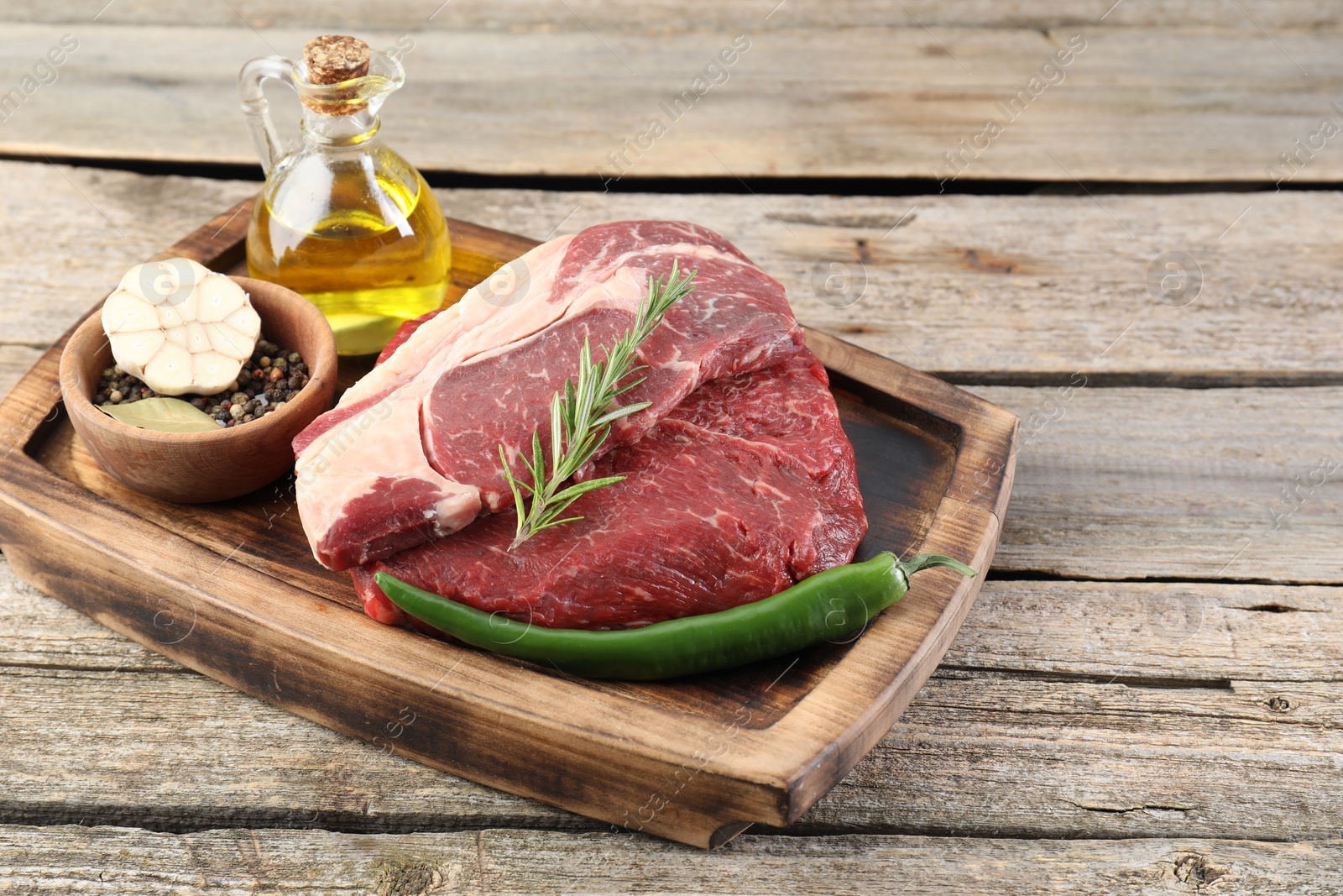 Photo of Fresh raw beef cut with spices and oil on wooden table. Space for text