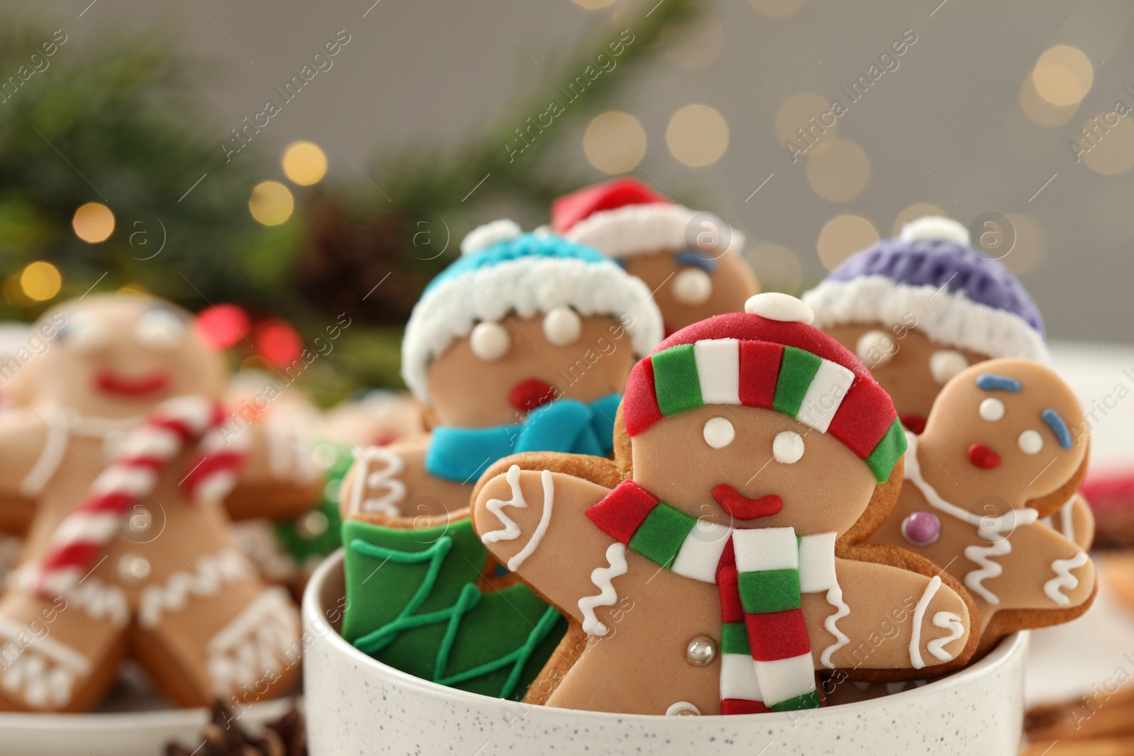 Photo of Delicious homemade Christmas cookies in bowl against blurred festive lights, closeup