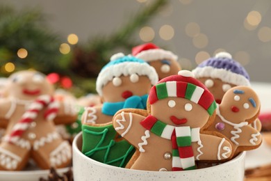 Photo of Delicious homemade Christmas cookies in bowl against blurred festive lights, closeup