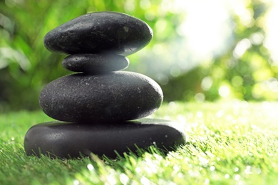 Photo of Stack of stones on green grass against blurred background, space for text. Zen concept