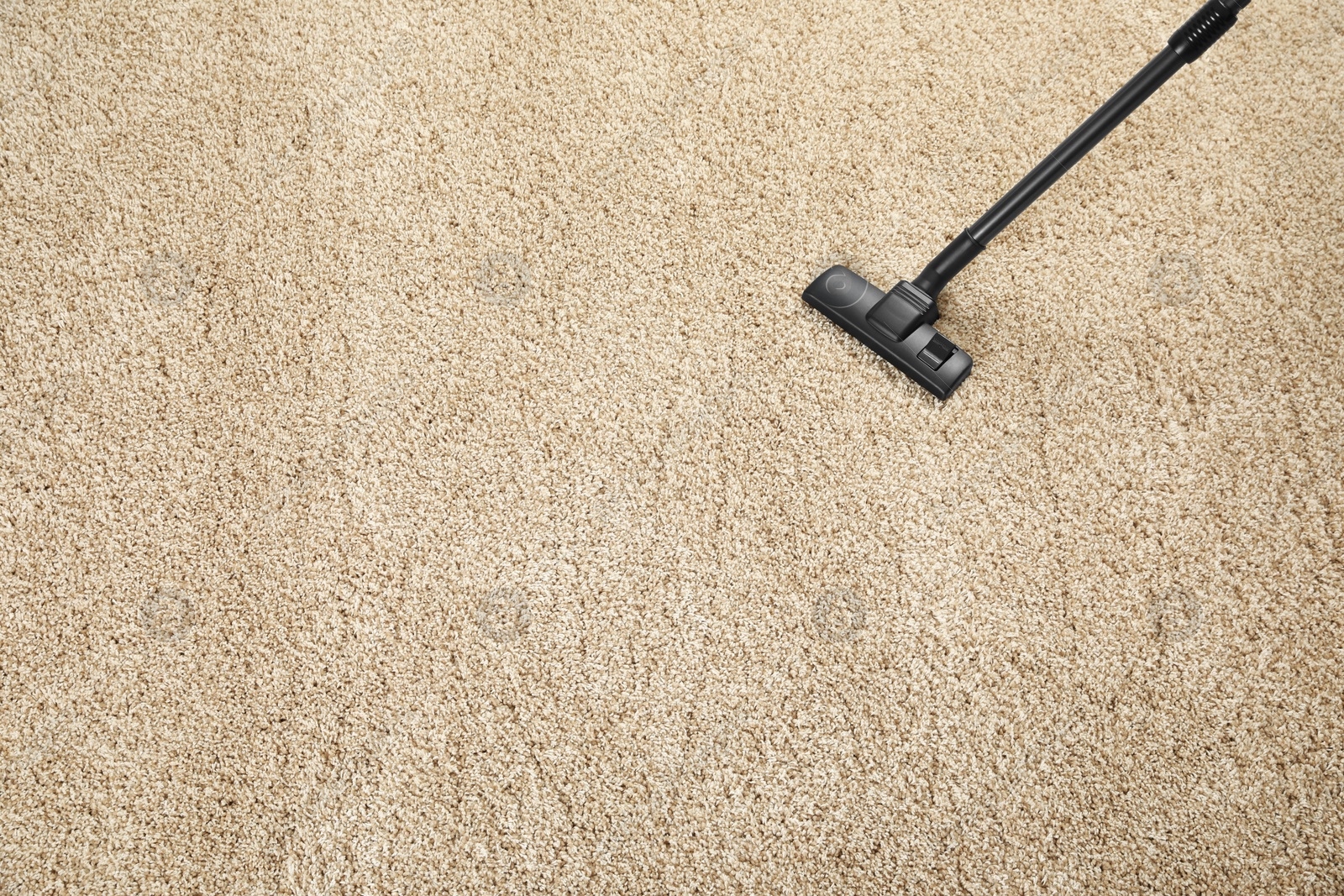 Photo of Removing dirt from beige carpet with modern vacuum cleaner, above view. Space for text