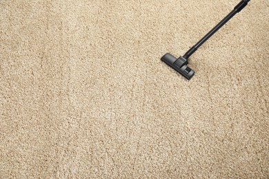 Removing dirt from beige carpet with modern vacuum cleaner, above view. Space for text