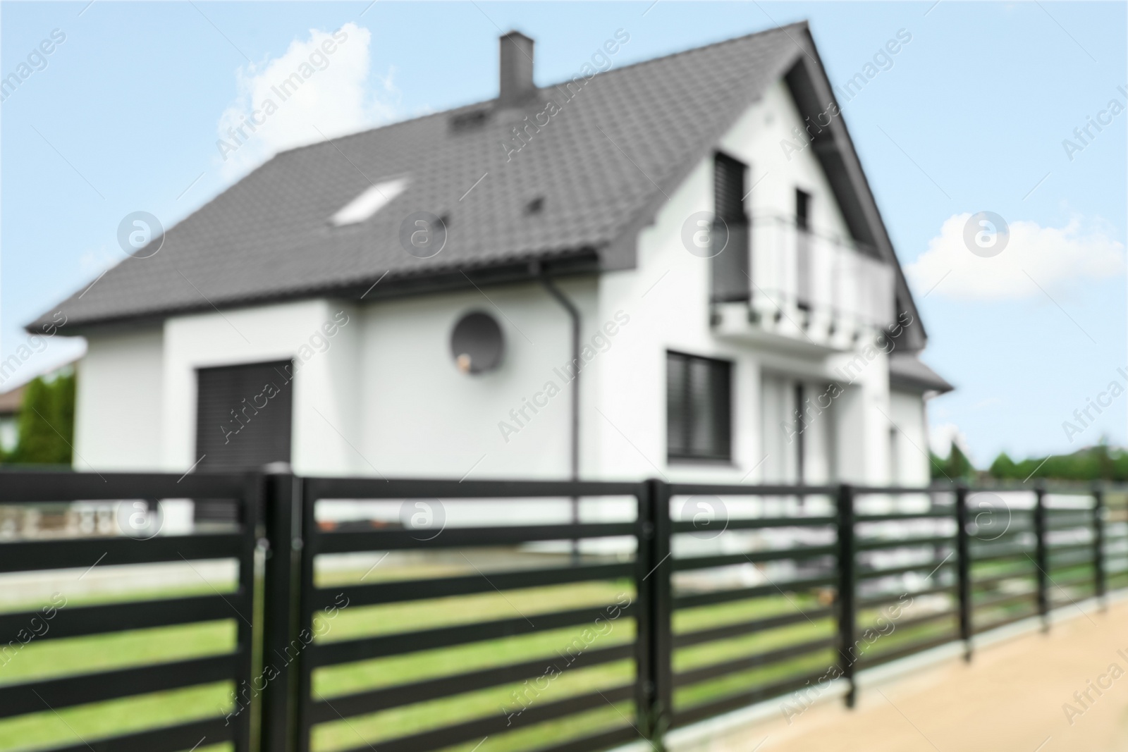 Photo of Blurred view of suburban street with beautiful house behind fence