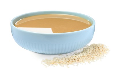 Photo of Tasty sesame paste in bowl and seeds on white background
