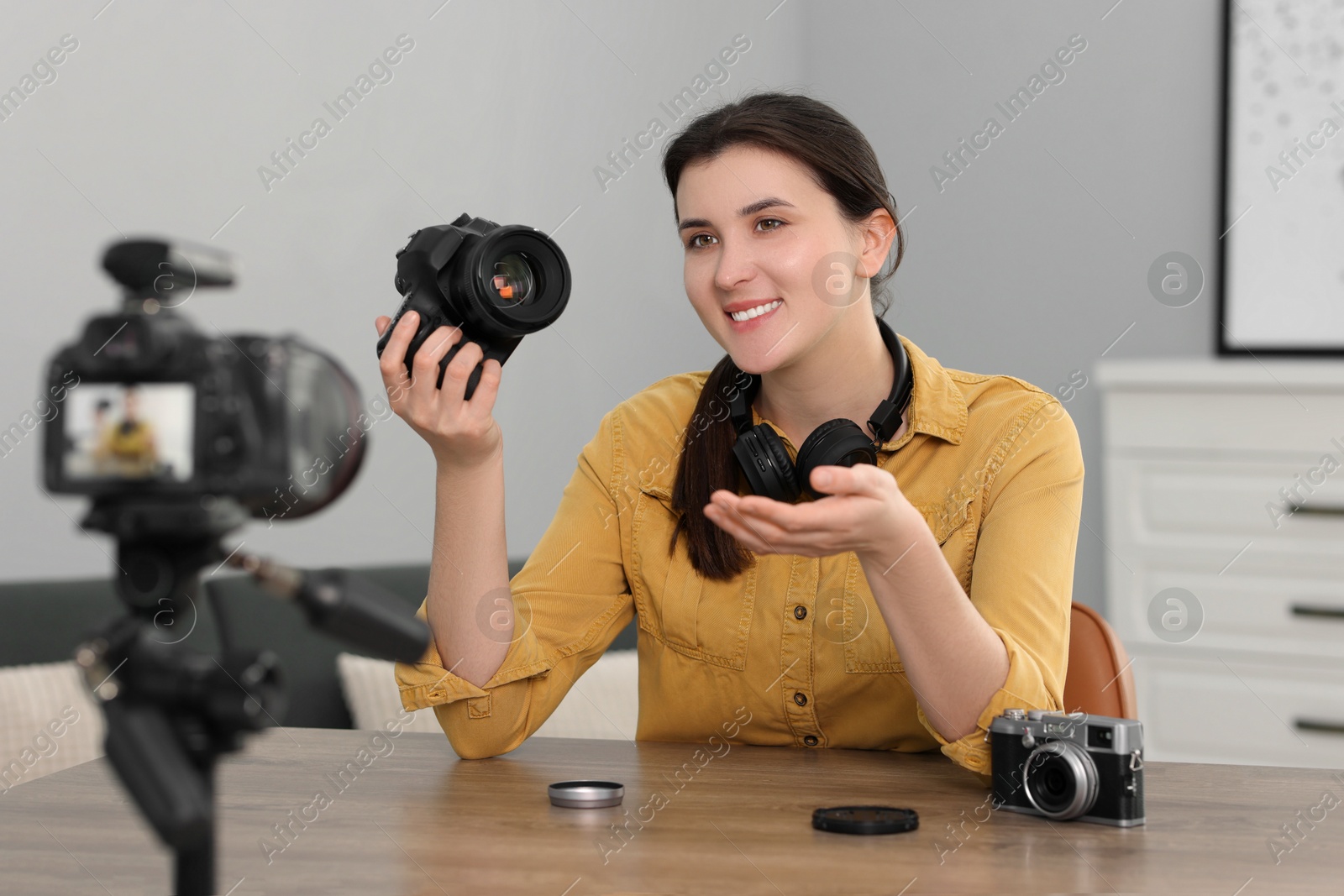 Photo of Smiling technology blogger recording video review about cameras at home