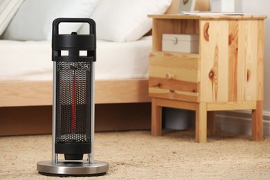Modern infrared heater on carpet in cozy room. Space for text