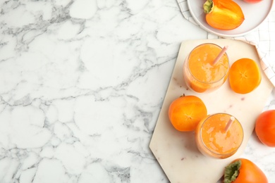 Tasty persimmon smoothie with straws and fresh fruits on white marble table, flat lay. Space for text