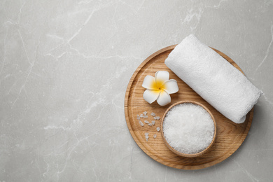 Photo of Sea salt, towel and flower on grey marble table, top view with space for text. Spa treatment