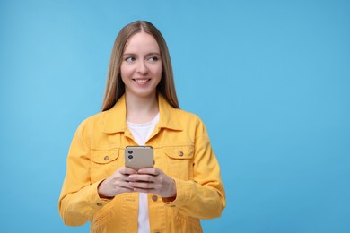 Photo of Woman sending message via smartphone on light blue background, space for text