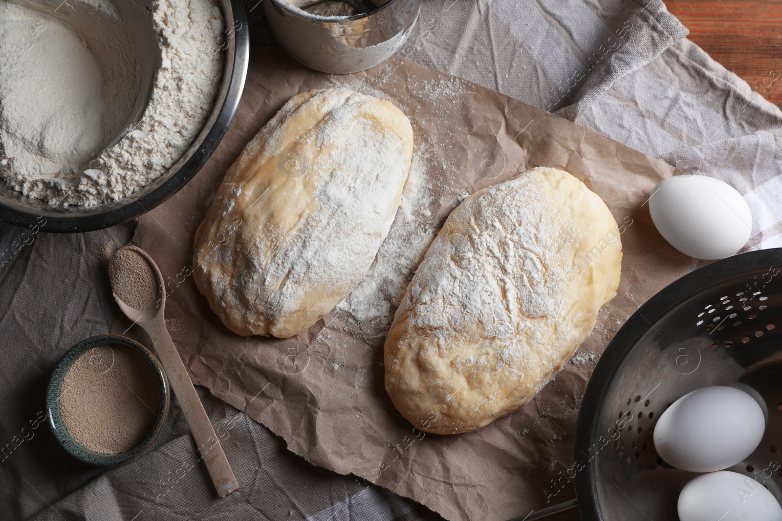 Photo of Raw dough, eggs and flour on wooden table, flat lay. Cooking ciabatta