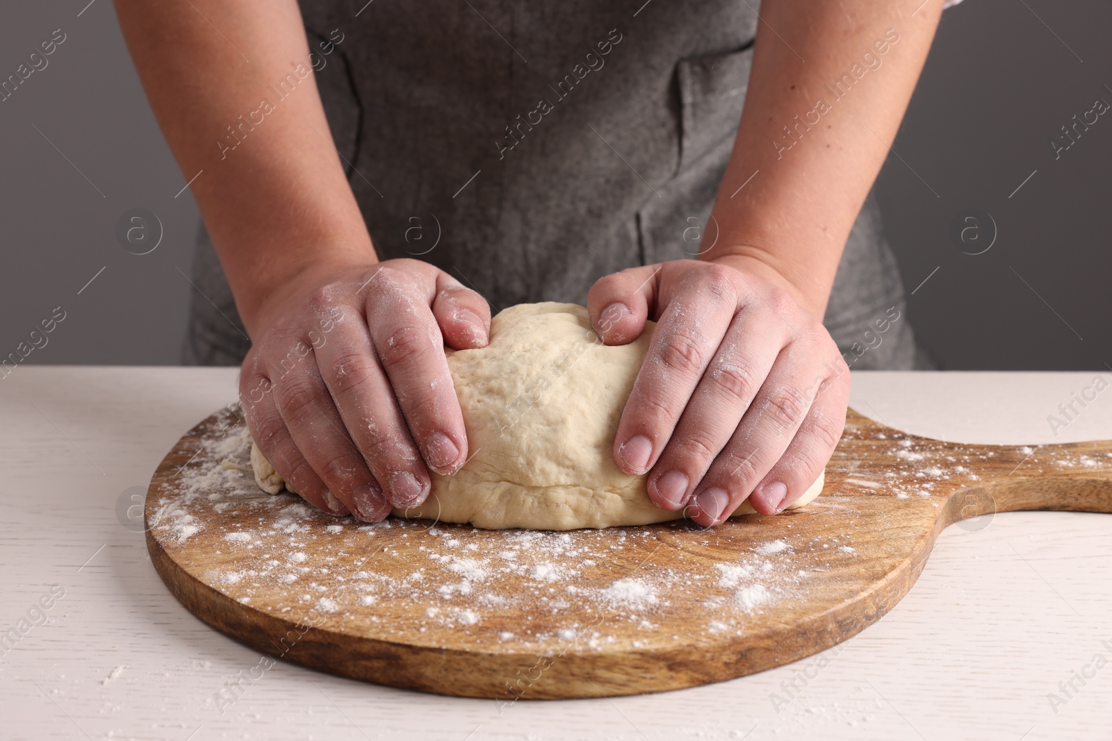 Photo of Man kneading dough at table near grey wall, closeup