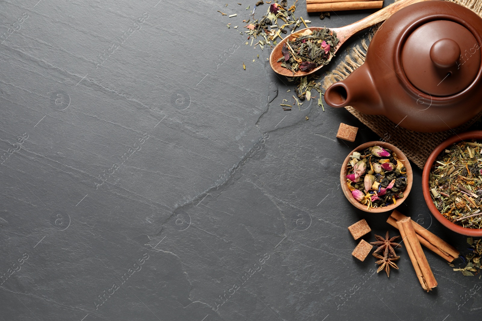 Photo of Flat lay composition with different dry teas on grey table, space for text