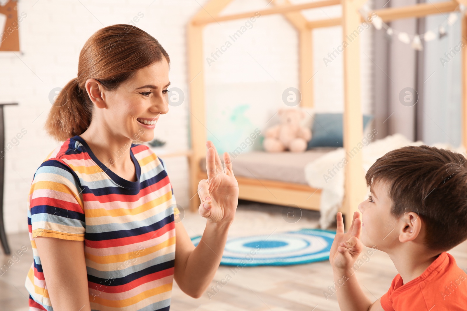 Photo of Hearing impaired mother and her child talking with help of sign language indoors