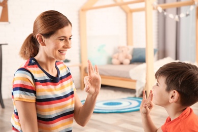 Photo of Hearing impaired mother and her child talking with help of sign language indoors